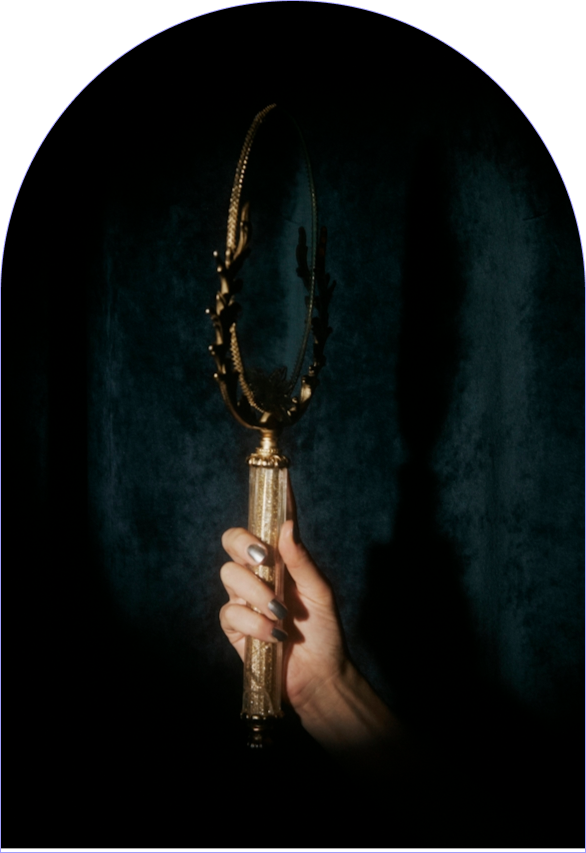A hand holding an ornate golden handheld mirror, representing self reflection and introsepction.
