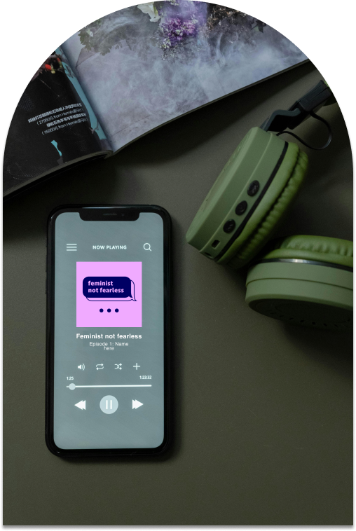 Image of the Feminist, not Fearless podcast playing on iphone, on a desk with green headphones and a magazine.